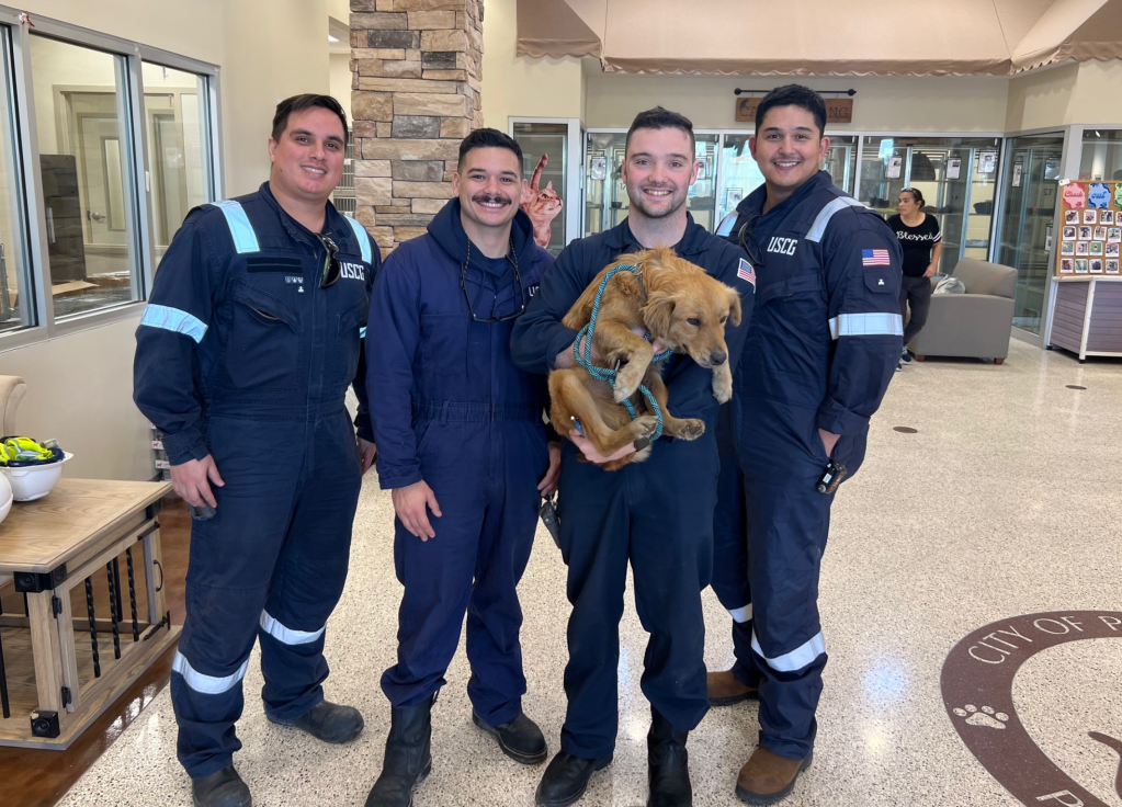 Member of U.S. Coast Guard posing after rescuing Connie the Container Dog